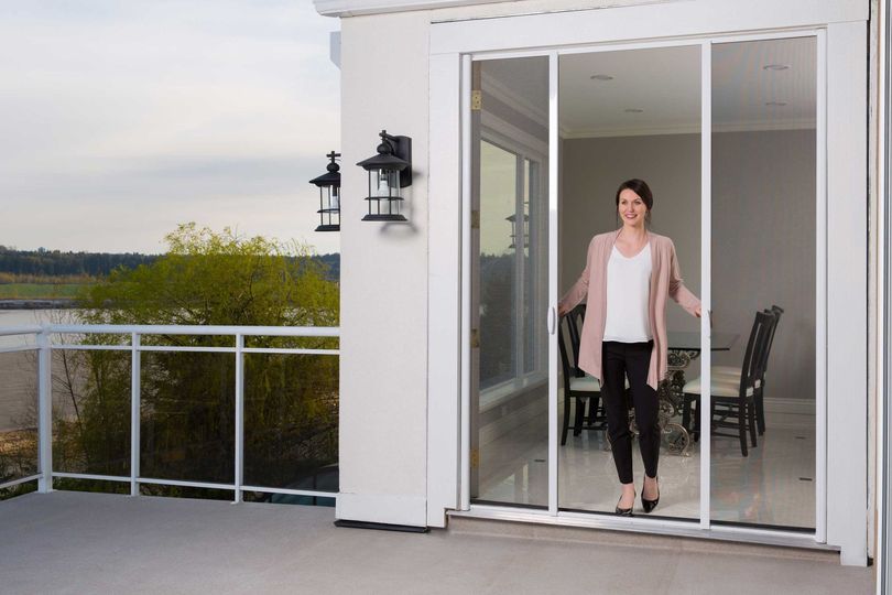 woman coming out of her french doors on to her deck, opening a retractable screen in chicago